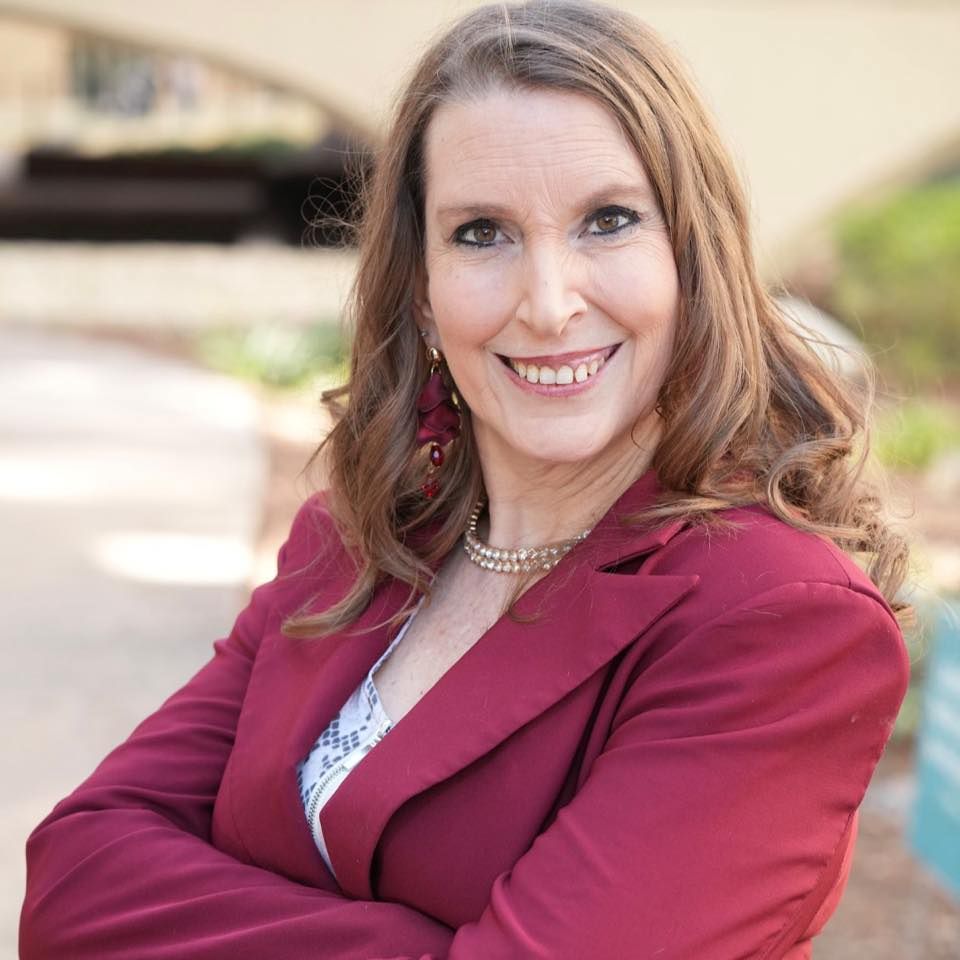 Dr. Diane Dye, founder of Enact Studios, smiling in a burgundy jacket.